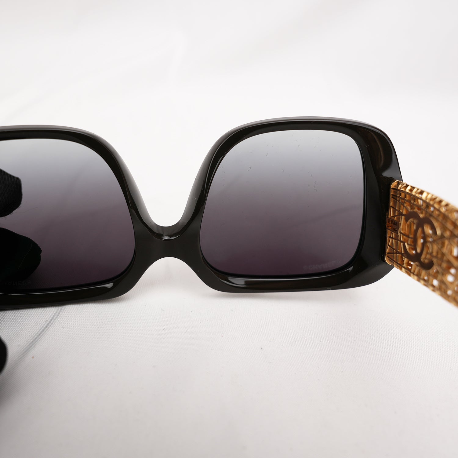 Chanel occhiali da sole neri con aste dorate effetto intrecciato CC